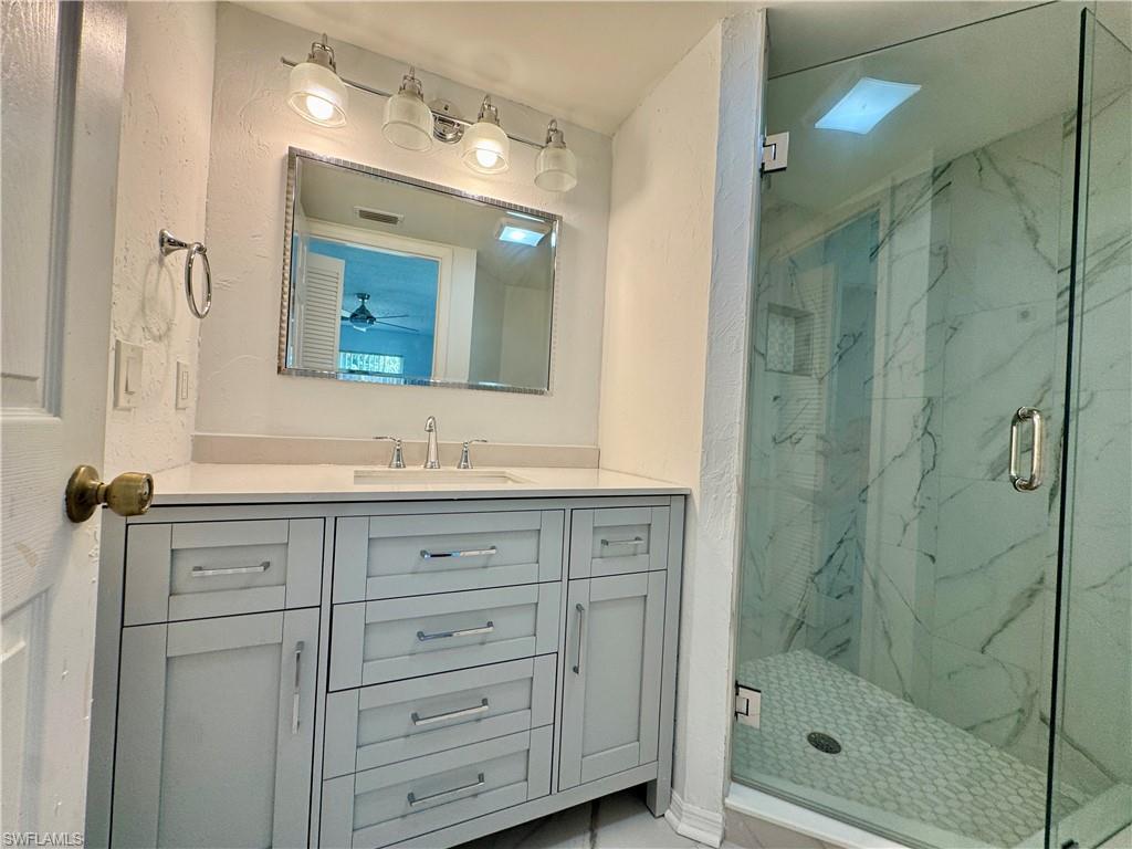 661 Squire Circle, Unit 101 Naples, FL 34104 - Photo 2 of 25 a bathroom with a shower sink and mirror