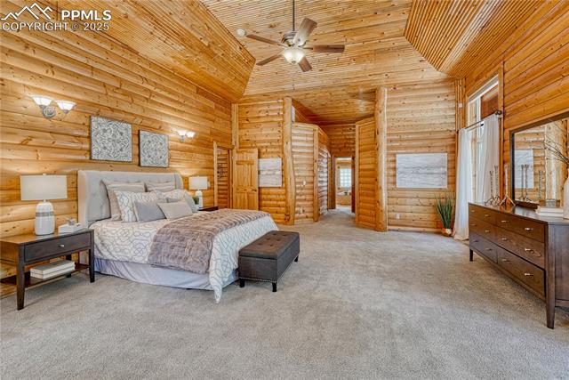 15975 Winding Trail Road Colorado Springs, CO 80908 - Photo 24 of 50 A stunning Primary Suite with 10-foot high log walls and a handcrafted coffered wood ceiling—rustic elegance at its finest