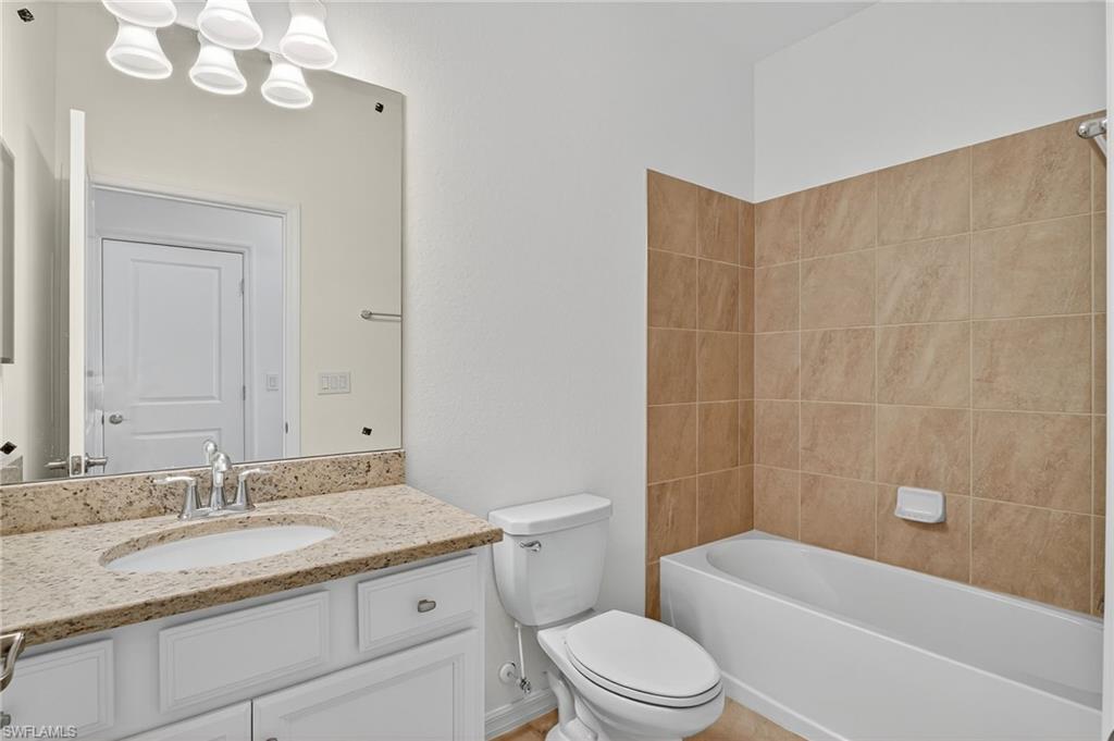 2126 Hamlin Street Naples, FL 34120 - Photo 18 of 38 a bathroom with a granite countertop sink a toilet and bathtub