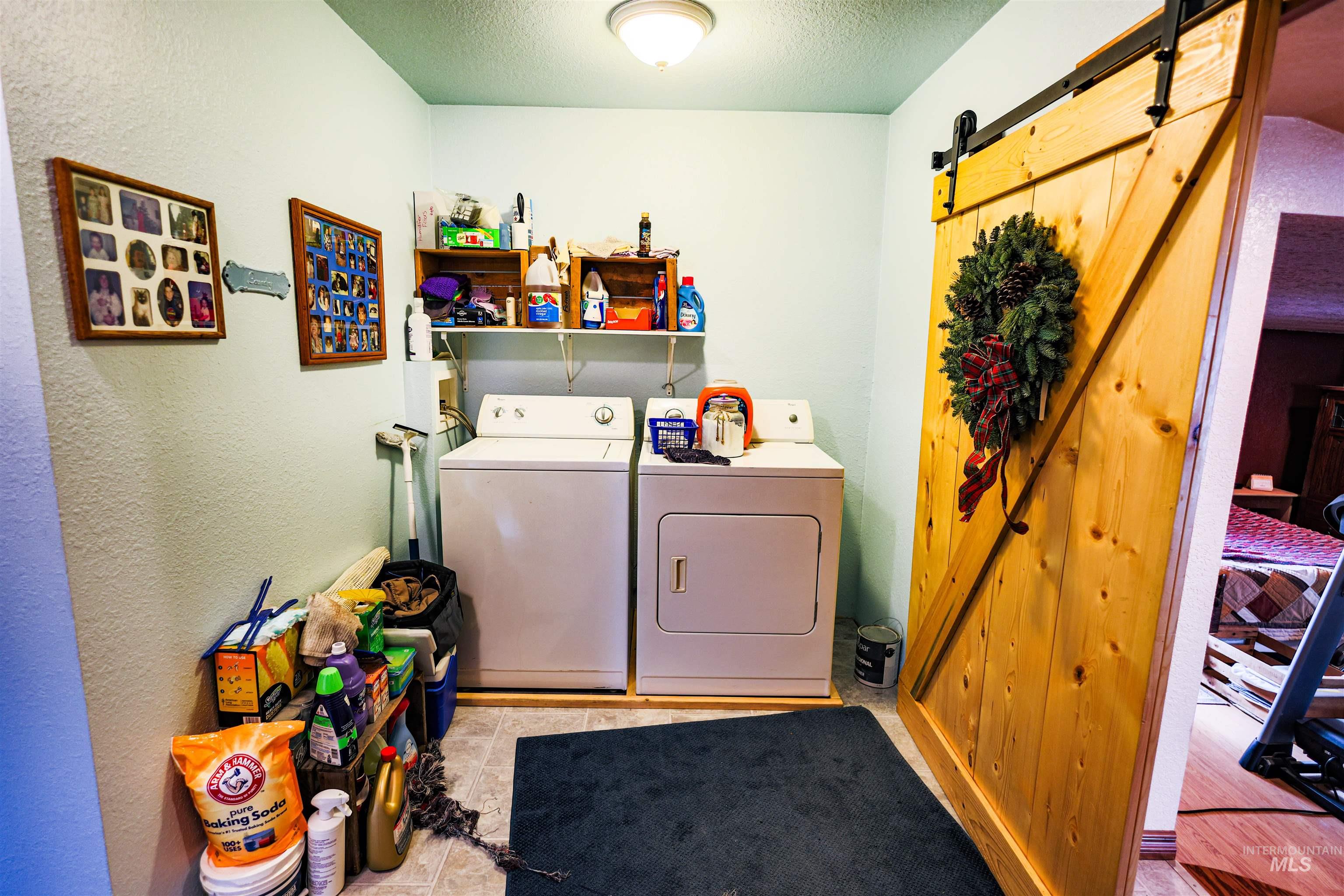 804 Maple Street Kamiah, ID 83536 - Photo 9 of 50 Laundry area with a barn door, a textured ceiling, a textured wall, and separate washer and dryer
