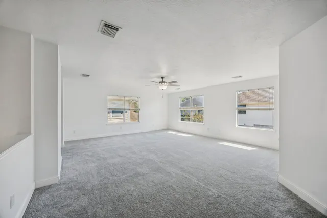 an empty room with windows and ceiling fan