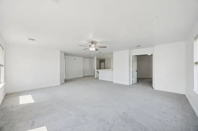an empty room with a windows and chandelier fan