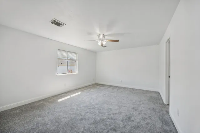 an empty room with a chandelier fan and windows