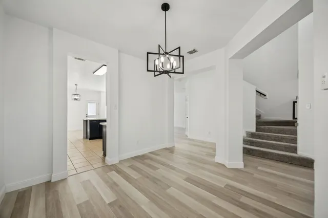 a view of empty room with wooden floor and kitchen