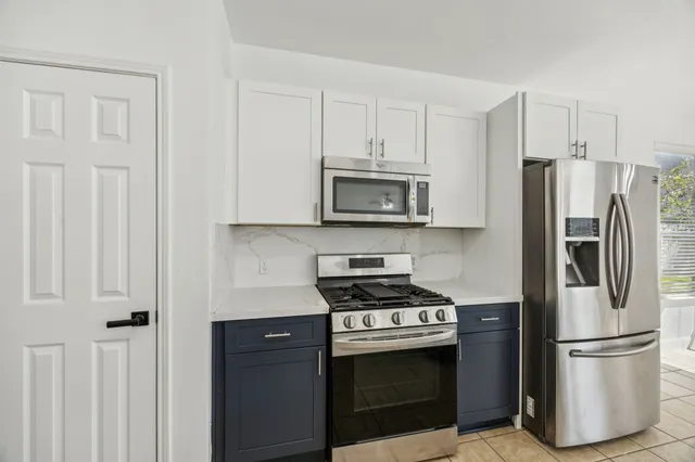 a kitchen with stainless steel appliances white cabinets and a stove top oven