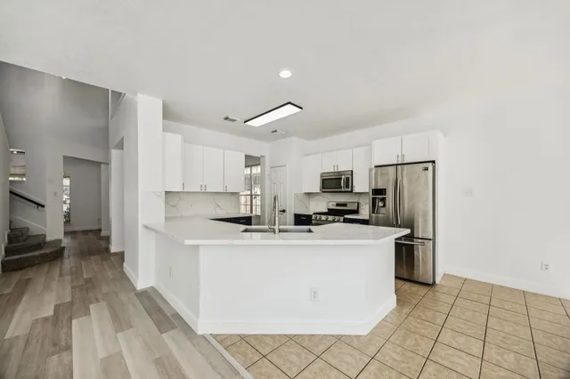 a kitchen with kitchen island a stove a refrigerator a sink dishwasher with a dining table and chairs