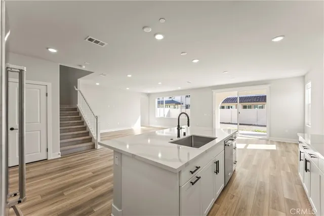 a kitchen with center island wooden floor and a sink