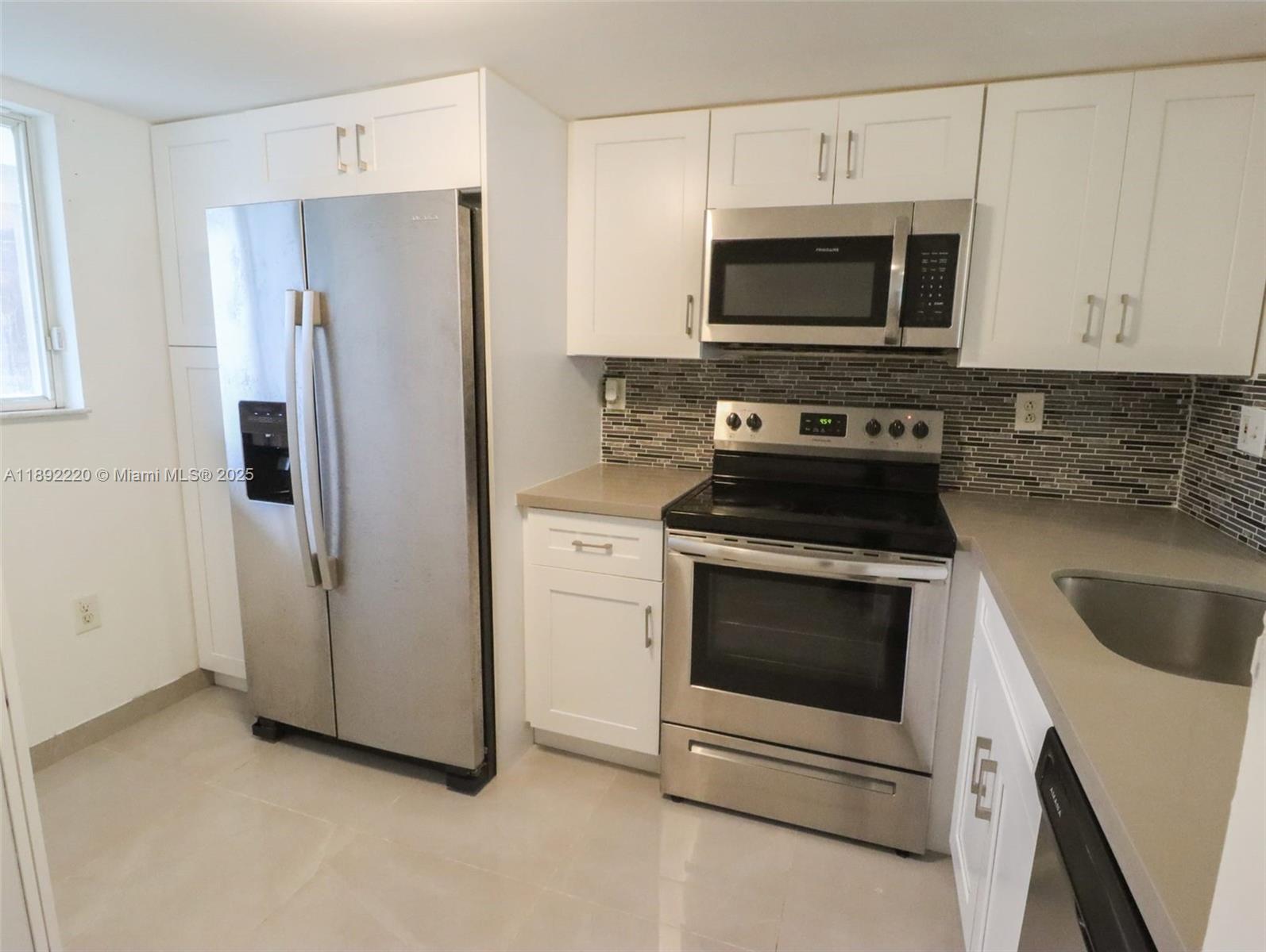 a kitchen with stainless steel appliances white cabinets a stove a microwave and a refrigerator