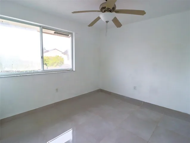 an empty room with windows and a ceiling fan