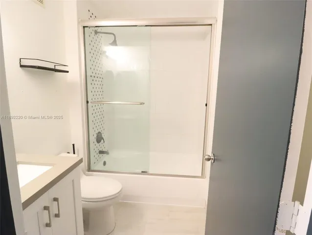 a bathroom with a granite countertop bathtub shower sink vanity and toilet