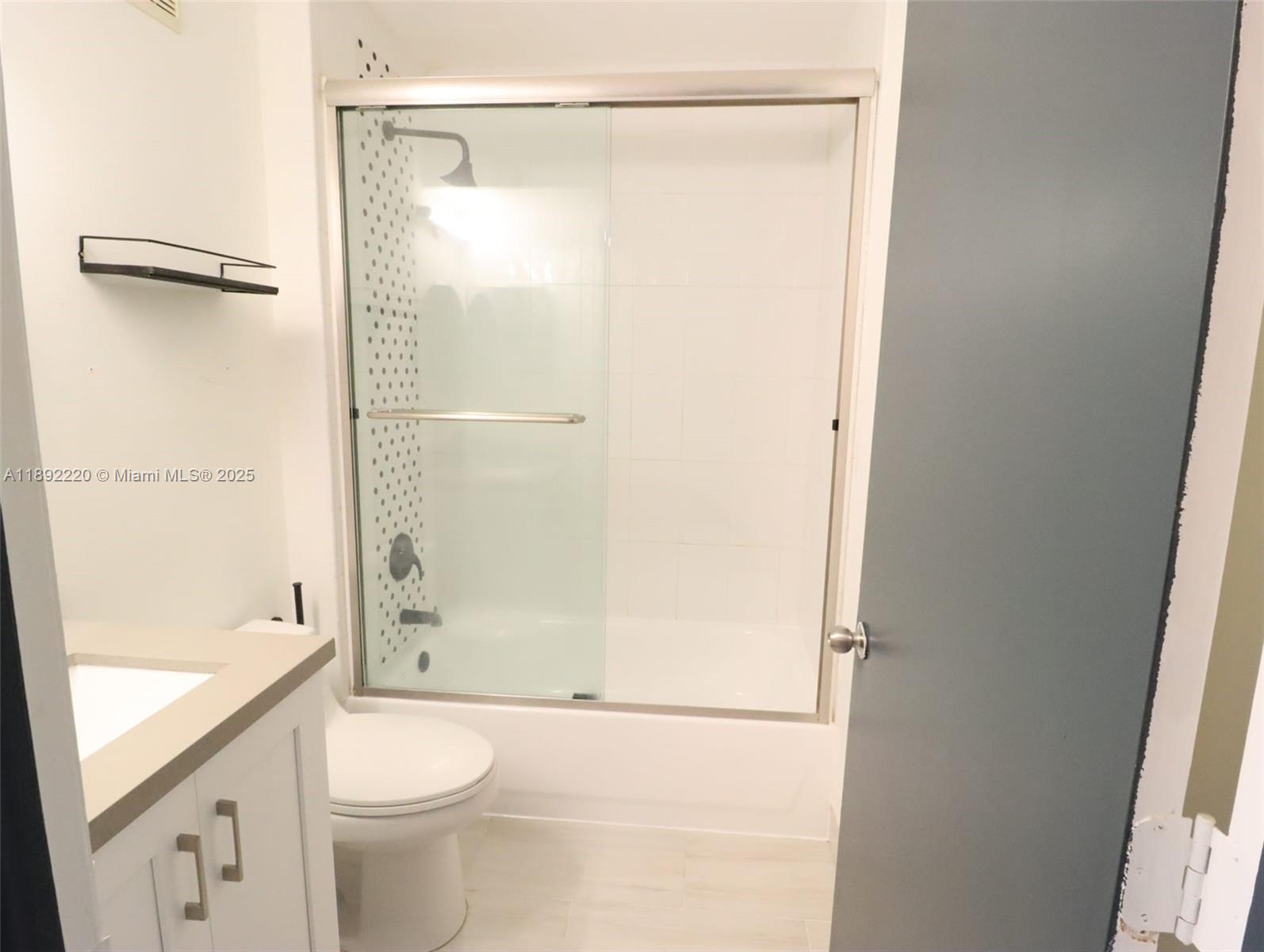 14010 Northeast 3rd Court, Unit 1 Miami, FL 33161 - Photo 8 of 26 a bathroom with a granite countertop bathtub shower sink vanity and toilet