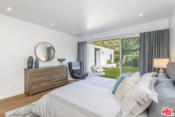 a bedroom with a bed a lamp and large window with outer view