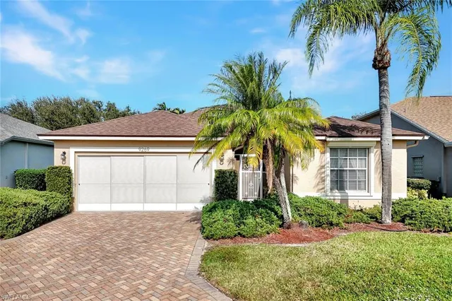 front view of a house with a yard and palm trees