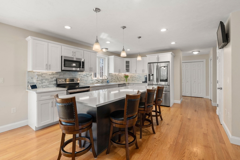 5 Glebe Street Rehoboth, MA 02769 - Photo 4 of 42 a kitchen with kitchen island granite countertop wooden floors and white cabinets