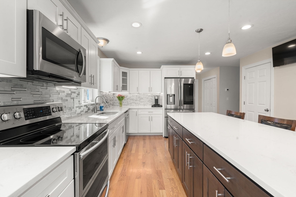 5 Glebe Street Rehoboth, MA 02769 - Photo 6 of 42 a large kitchen with stainless steel appliances kitchen island granite countertop a stove a sink dishwasher and a microwave with wooden floor