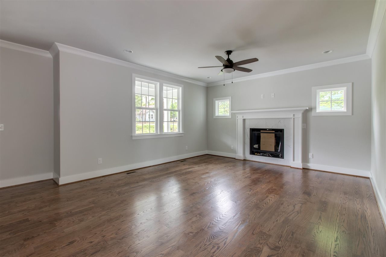 2929 Chapel Hill Road Durham, NC 27707 - Photo 7 of 25 an empty room with wooden floor fireplace and windows