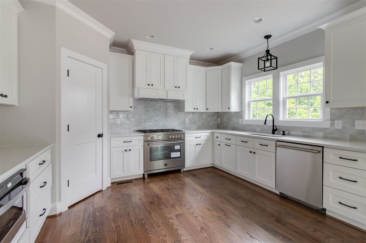 2929 Chapel Hill Road Durham, NC 27707 - Photo 9 of 25 a kitchen with stainless steel appliances white cabinets and wooden floors