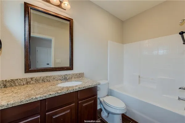 a bathroom with a granite countertop sink a toilet and a bathtub