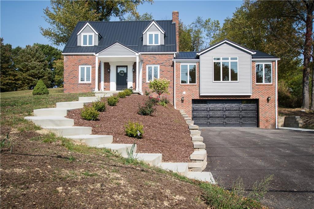Front view of the property.  Large driveway to park 4-6 cars.  Manicured landscaping and lawn.  New metal roof.