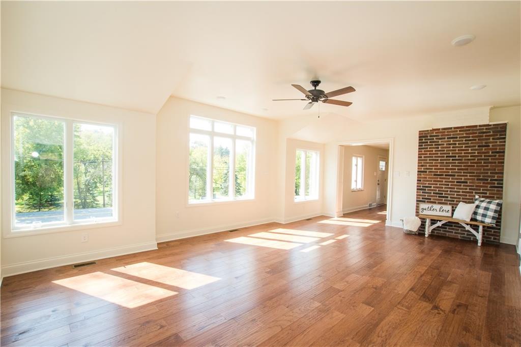 Large living room with lots of windows to allow the sunlight to bounce off the beautiful floors.  The exposed brick adds charm and a farmhouse feel to the home.  
