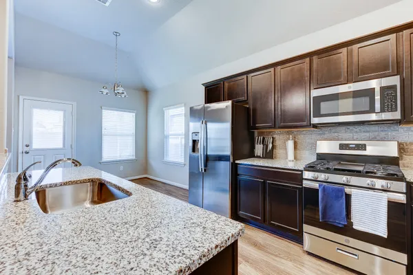 a kitchen with stainless steel appliances granite countertop a sink stove and refrigerator