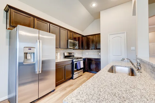 a kitchen with stainless steel appliances granite countertop a refrigerator sink and stove
