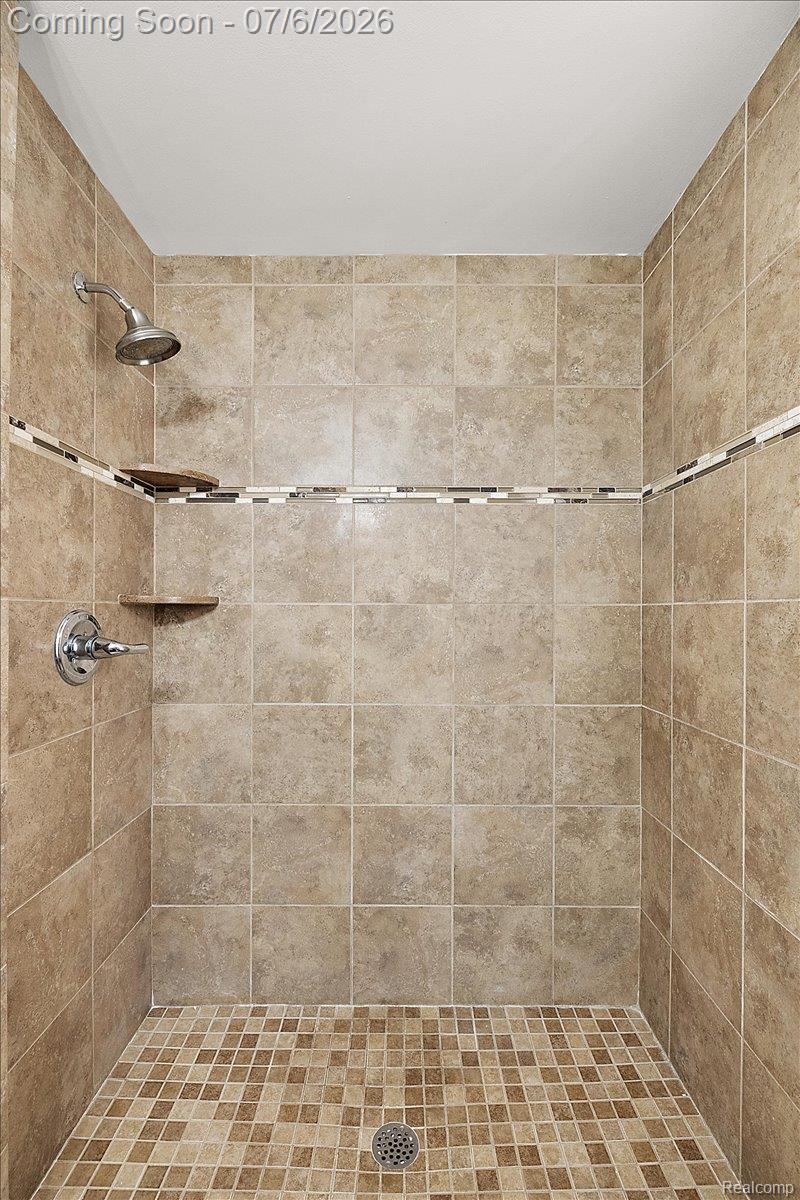 1051 Devonshire Road Grosse Pointe, MI 48230 - Photo 53 of 98 Tiled shower stall featuring square beige wall tiles with a decorative mosaic accent strip