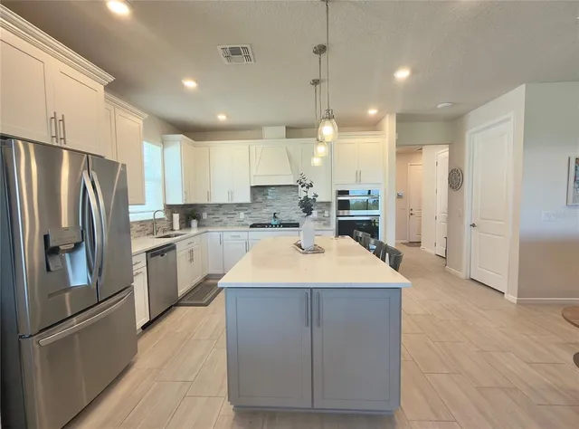 a large kitchen with stainless steel appliances kitchen island a stove a refrigerator a sink and a refrigerator