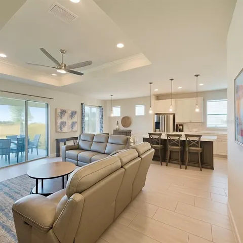 a living room with furniture a table and kitchen view