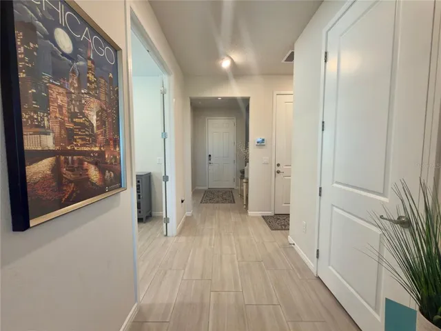 a view of a hallway with wooden floor and a bathroom