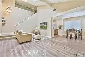 a living room with couches and kitchen view with wooden floor