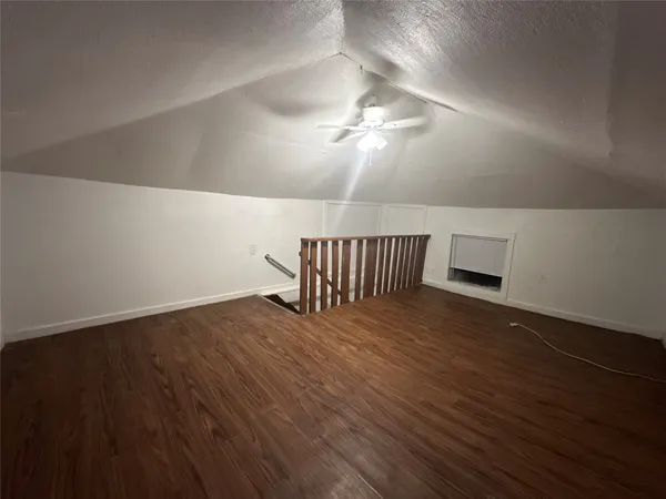a view of a room with wooden floor and a ceiling fan