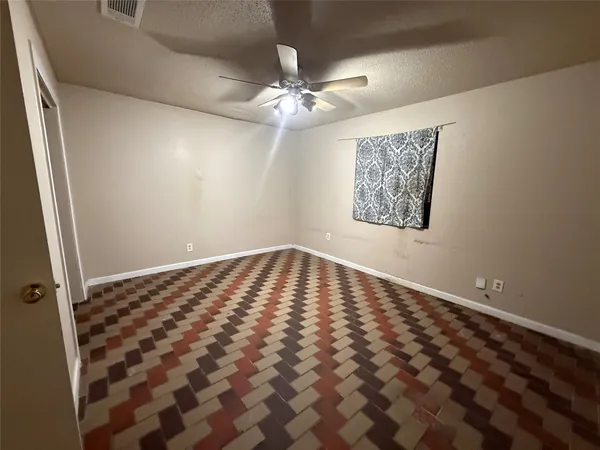 an empty room with wooden floor and fan