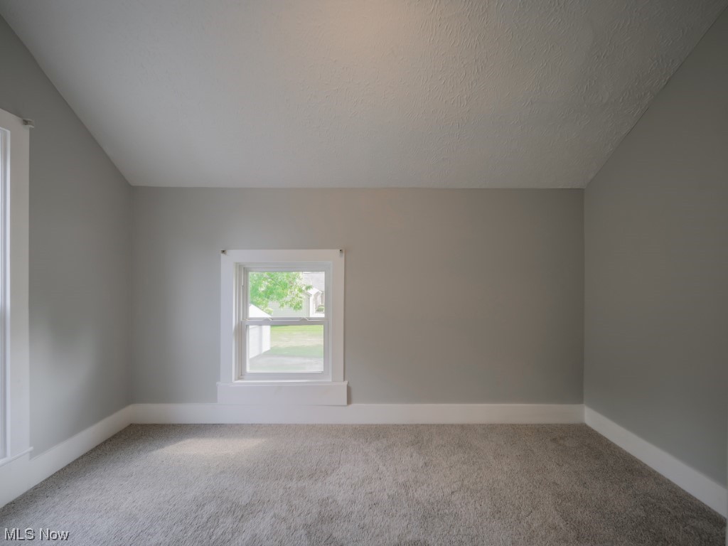 39330 Chestnut Ridge Road Elyria, OH 44035 - Photo 23 of 32 Empty room with light carpet, vaulted ceiling, and a textured ceiling