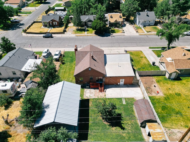 673 East 700 South Springville, UT 84663 - Photo 4 of 43 Brick exterior property featuring a hip roof, an additional detached building with a metal roof, and a paved driveway