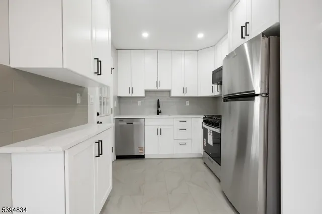 a kitchen with white cabinets and stainless steel appliances