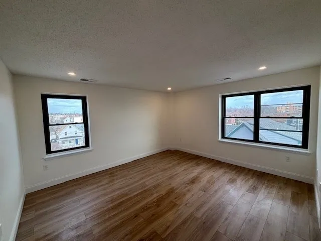 a view of an empty room with window and wooden floor