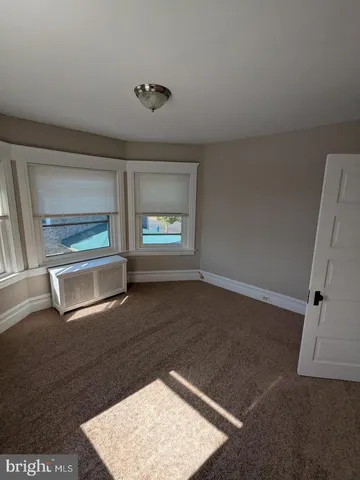 an empty room with wooden floor cabinet and windows
