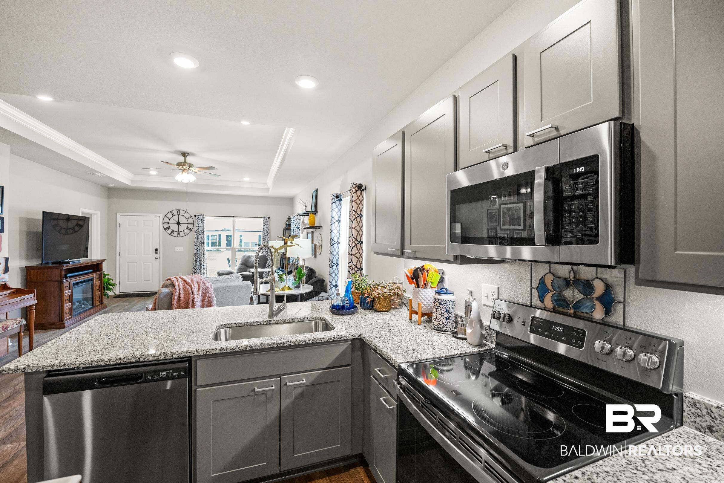 24139 Veranda Circle Elberta, AL 36530 - Photo 13 of 40 Kitchen with gray cabinetry, a sink, a tray ceiling, stainless steel appliances, and a peninsula