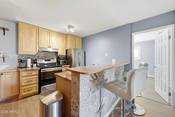 a kitchen with stainless steel appliances granite countertop a stove a refrigerator a sink a dining table and chairs with wooden floor