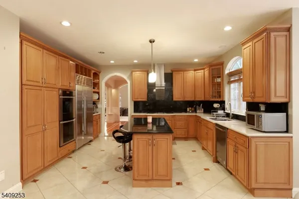 a large kitchen with kitchen island a counter top space a sink stainless steel appliances and cabinets