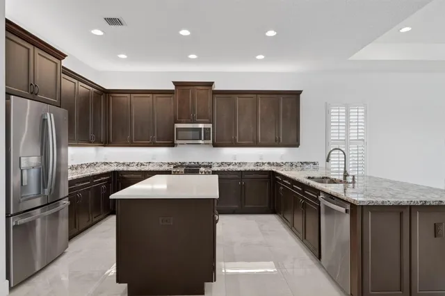 a kitchen with stainless steel appliances granite countertop a stove a sink and a refrigerator