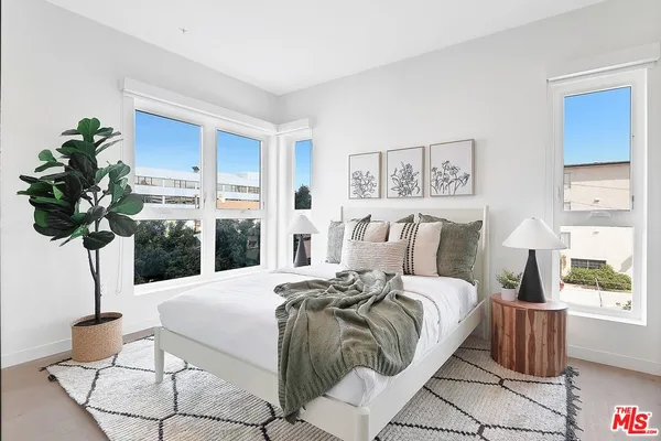 a bedroom with a large bed and a potted plant