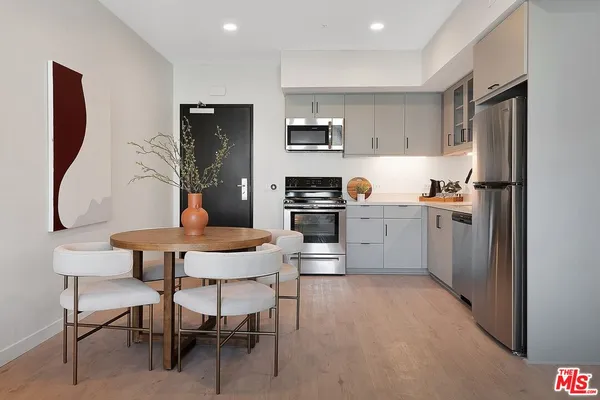 a kitchen with stainless steel appliances a dining table chairs refrigerator and sink