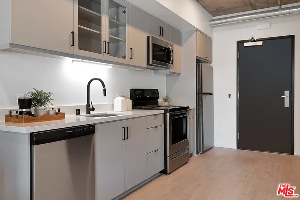 a kitchen with stainless steel appliances a sink a refrigerator and cabinets