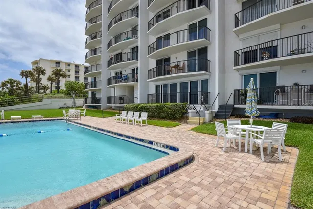 a view of swimming pool with lawn chairs and large trees