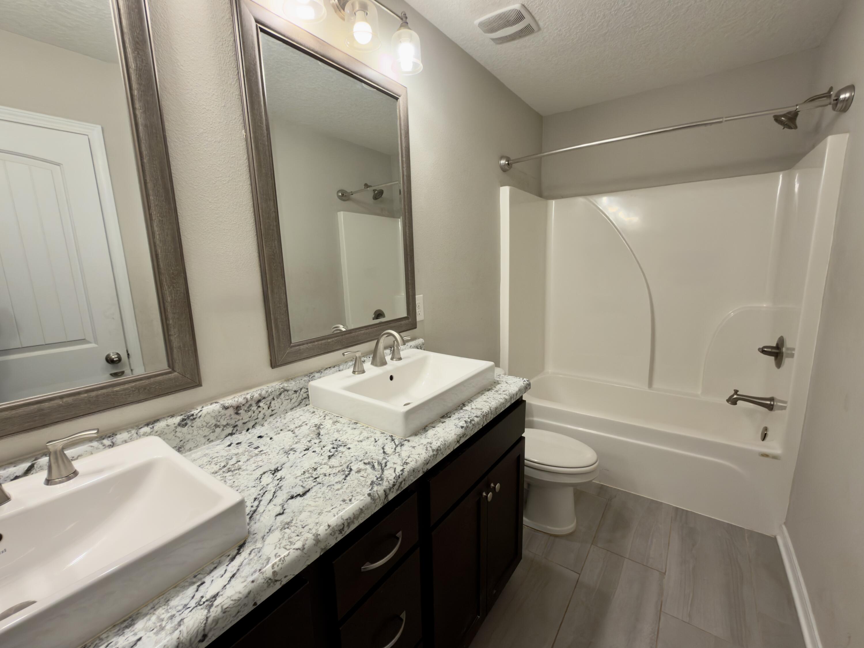 201 Wainwright Drive Crestview, FL 32539 - Photo 18 of 26 a bathroom with a granite countertop sink a toilet a mirror and shower