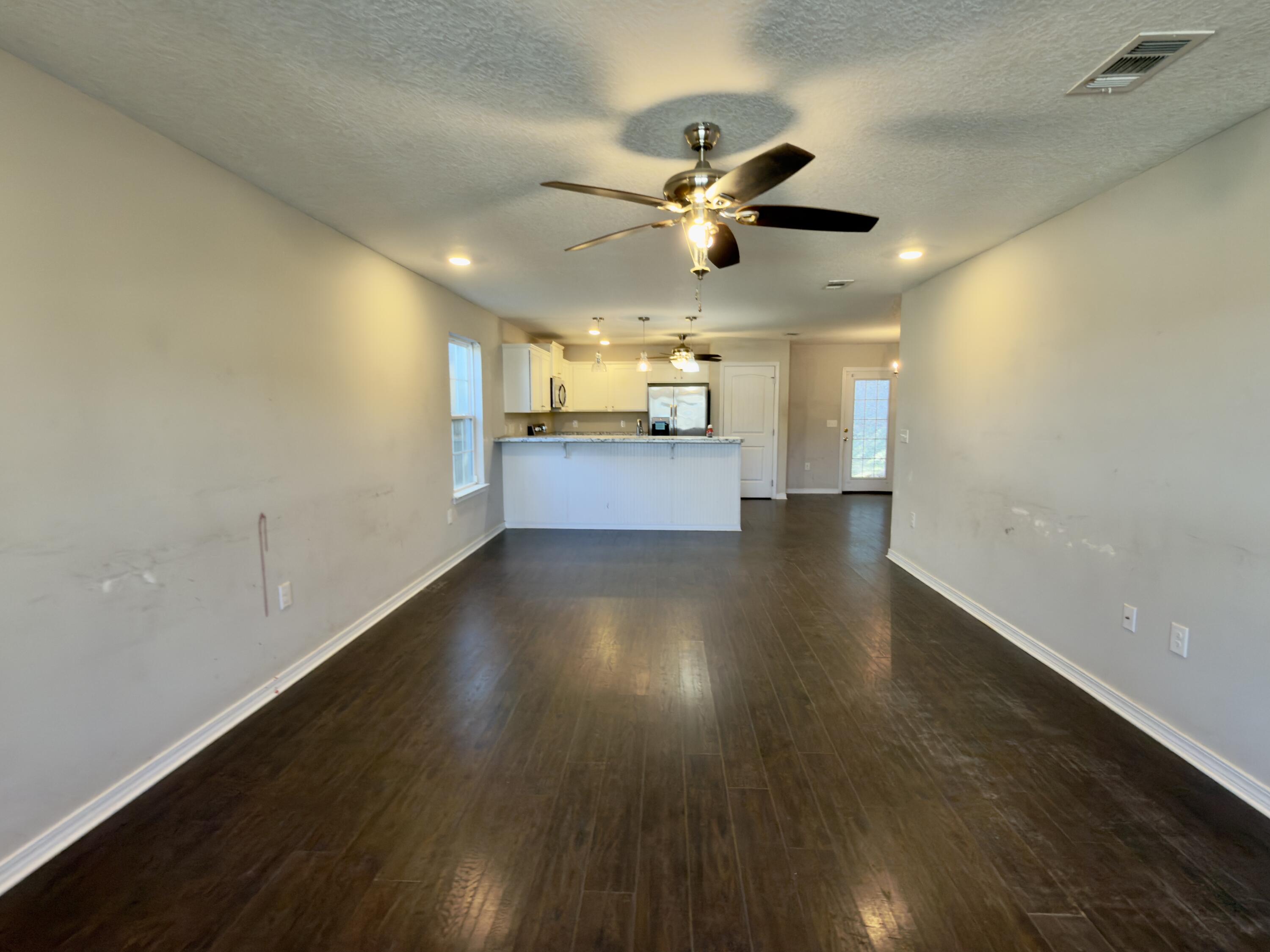 201 Wainwright Drive Crestview, FL 32539 - Photo 2 of 26 a view of a room with wooden floor a ceiling fan and windows