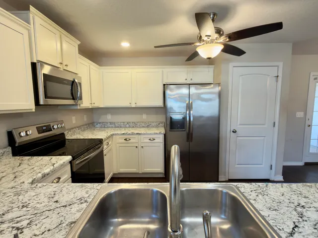 a kitchen with stainless steel appliances granite countertop a sink a stove and a refrigerator
