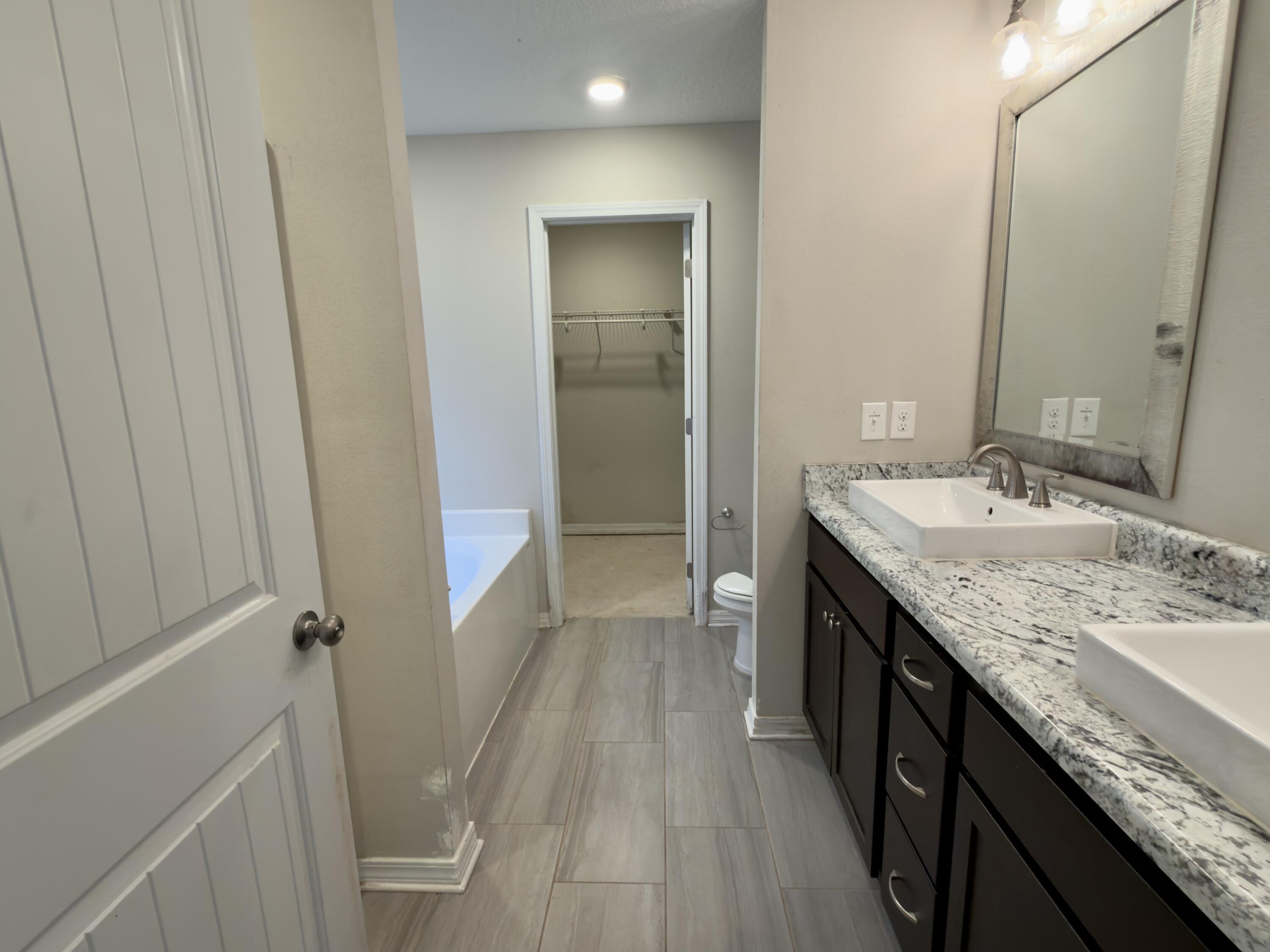 201 Wainwright Drive Crestview, FL 32539 - Photo 9 of 26 a bathroom with a granite countertop sink a mirror and a shower